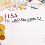 Desktop office desk, notebook, glasses, pen and documents with FLSA Fair Labor Standards Act on a tabl