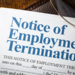 Notice of employment termination with pen on note pad and desk